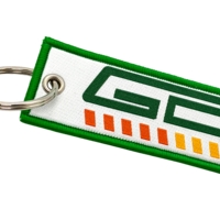 Weißer gewebter Schlüsselanhänger mit grünem Rand, mehrfarbigem Logo und Metallring.