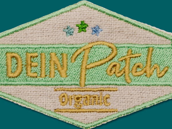 Organic-Patch aus Biobaumwolle - natürlicher, leicht beigefarbener Untergrund mit aufgestickten Schriften und Formen