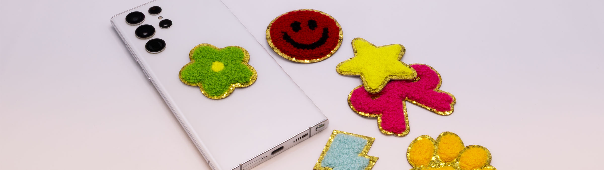 Eine Collage mit einigen Chenille-Patches mit Goldglitzer-Untergrund und einem Smartphone