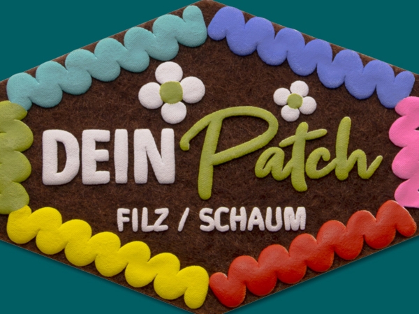 Aufnäher aus Filz / Schaum - auf einem dukelbraunen Filzuntergrund werden mehrfarbig Details aufgeschäumt - Optik eines Lebkuchenherzens
