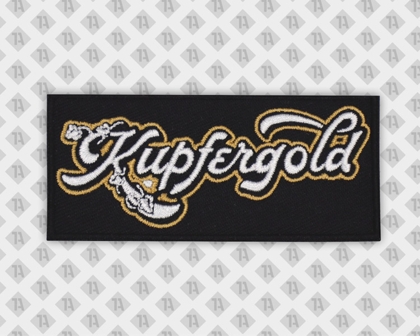 Gestickter Patch mit „Kupfergold“-Schriftzug in Weiß und Gold auf schwarzem Hintergrund