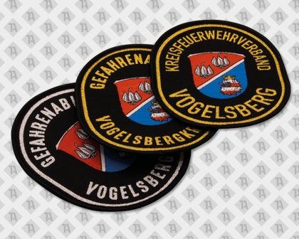 Mehrere runde Patches mit dem Vogelsberg-Wappen und umlaufenden Feuerwehr-Schriftzügen in verschiedenen Farbvarianten.
