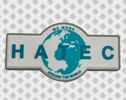 PVC-Patch mit HATEC-Logo und Weltkarte – 3D-Aufnäher mit Schriftzug „We work around the world“ in Türkis