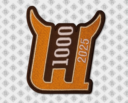 Hornförmiger Patch in Orange und Braun mit der Zahl „1000T“ und dem Jahr „2025“.