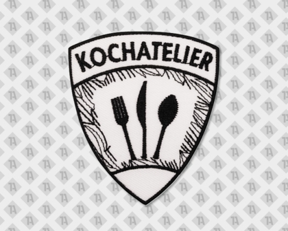 Wappenförmiger Patch mit schwarzer Stickerei, Schriftzug „Kochatelier“ und Bestecksymbolen Messer, Gabel und Löffel – eleganter Gastro-Aufnäher