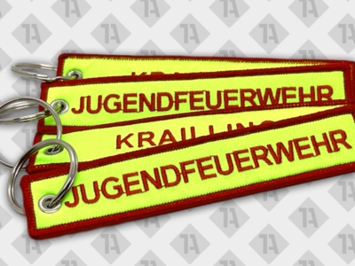 Neongelbe gewebte Schlüsselanhänger mit roter Schrift „Jugendfeuerwehr“ und Metallring.
