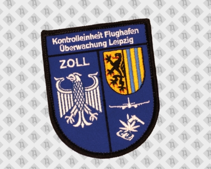 Schildförmiger Zoll Patch „Kontrolleinheit Flughafen Überwachung Leipzig“ mit Adler, Wappen, Flugzeug und stilisierter Pflanze