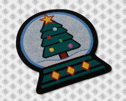 Gewebter Aufnäher/Patch im Weihnachtsnmotiv "Schneekugel" - grüner Baum im Schnee. Verschiedene farbige  Metallicgarne wurden verwendet