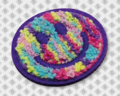 Bunter Smiley mit mehrfarbigem Chenillegarn und lilafarbenen, gestickten Rand und Gesicht