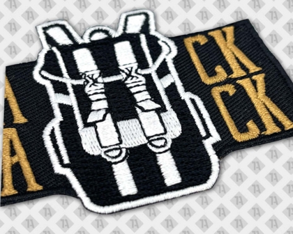Detailaufnahme eines gestickten Backpack-Patches in Schwarz, Weiß und Gold
