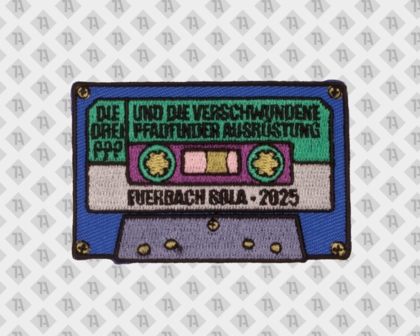 Rechteckiger Aufnäher in Form einer bunten Musikkassette mit mehreren Textfeldern und Jahreszahl 2025 im Retro-Design