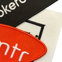 Standardhintergrund in verschiedenen Farben – schwarzes, weißes und rotes Patch mit gestickten Logos und Schriftzügen