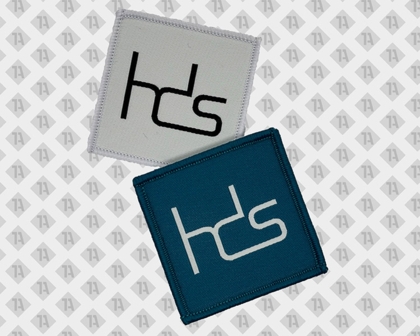 Zwei quadratische HDS-Aufnäher in Weiß und Blau mit gesticktem Logo